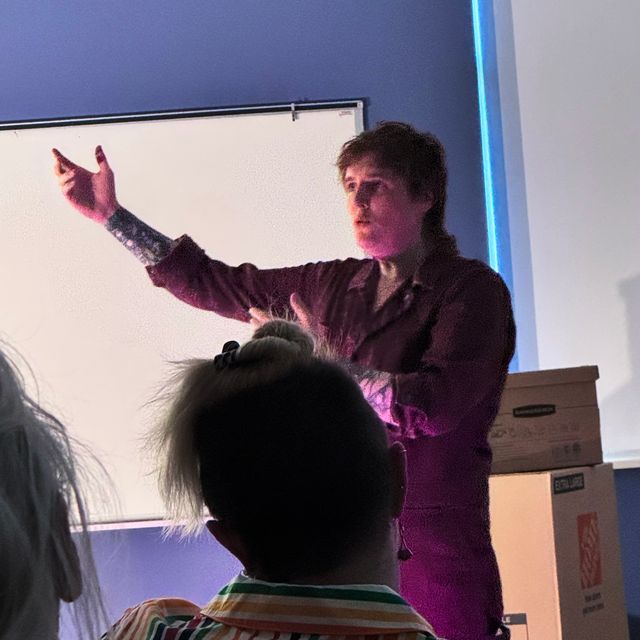 Miriam in a boiler suit gesturing with both arms