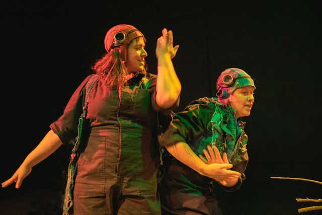 Kate Spear and Allison Blakeney mid-dance in boiler suits and aviator helmets