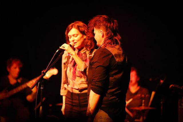 Julie and Lars at a mic, in front of the band