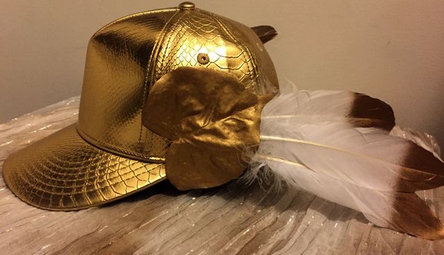 gold baseball cap, with a gold leaf and feathers