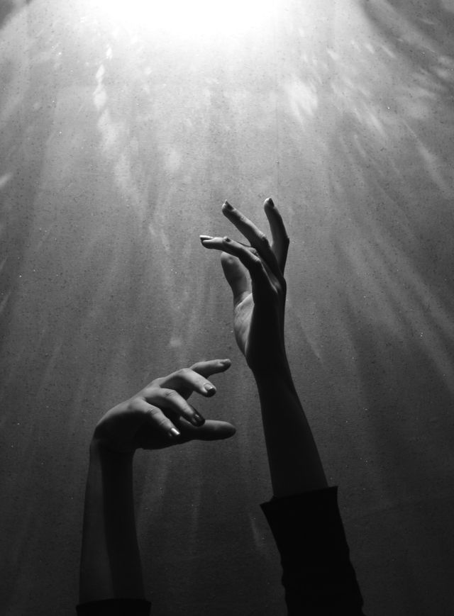 Hands grasping up towards light